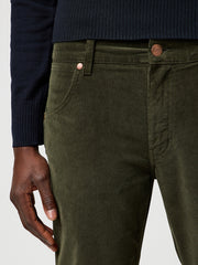Close-up of green corduroy pants with a navy sweater and hand visible.