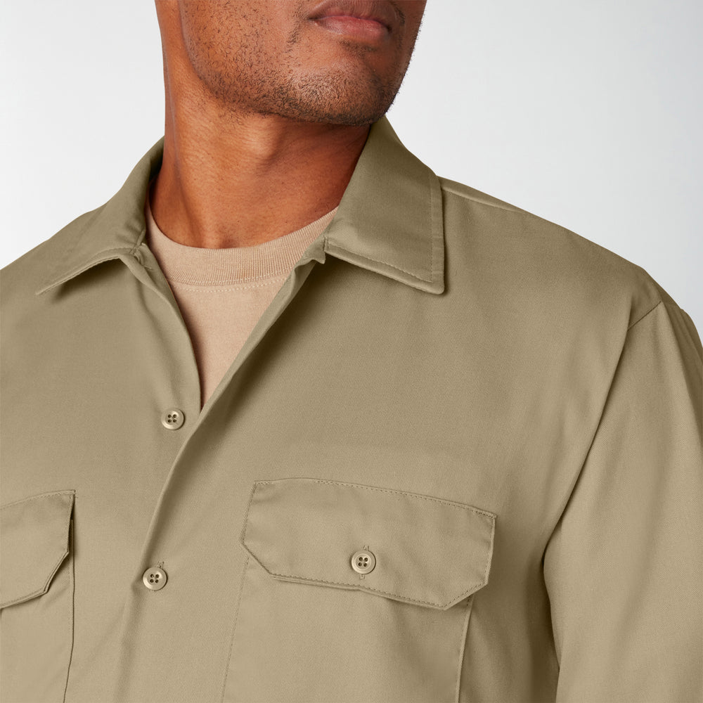Close-up of a person wearing a beige button-up shirt against a plain background
