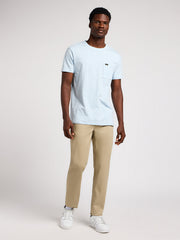 Man wearing a light blue t-shirt and beige pants on a white background