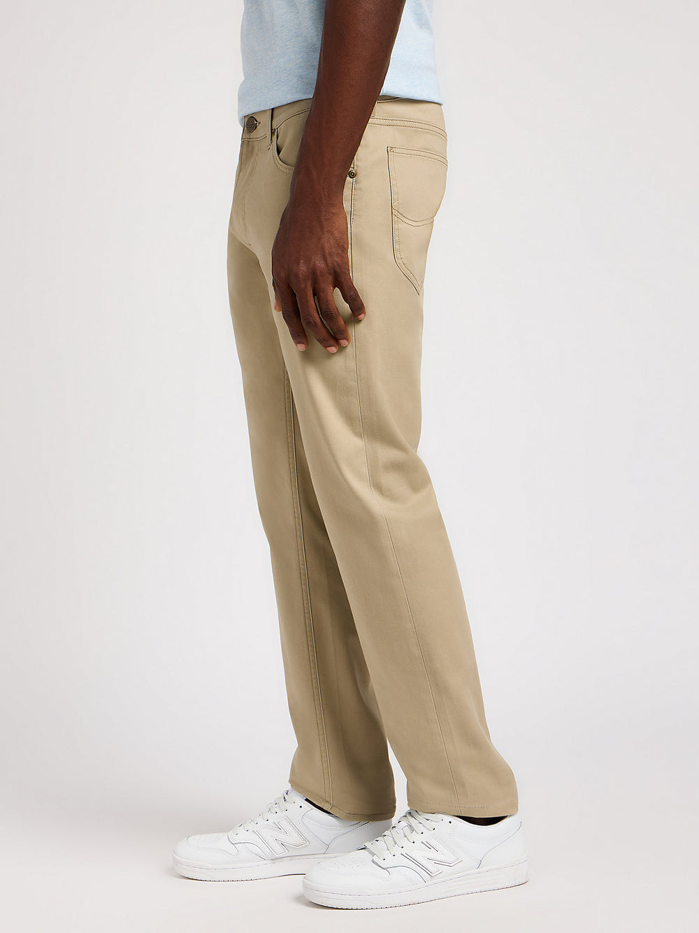 Person wearing beige pants and white sneakers on a plain background