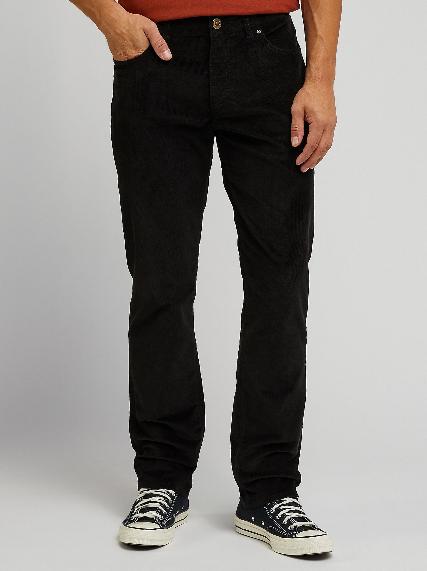 Person wearing black jeans and black sneakers on a plain background