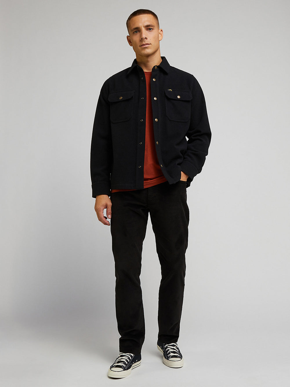 Man wearing a black jacket and pants on a gray background