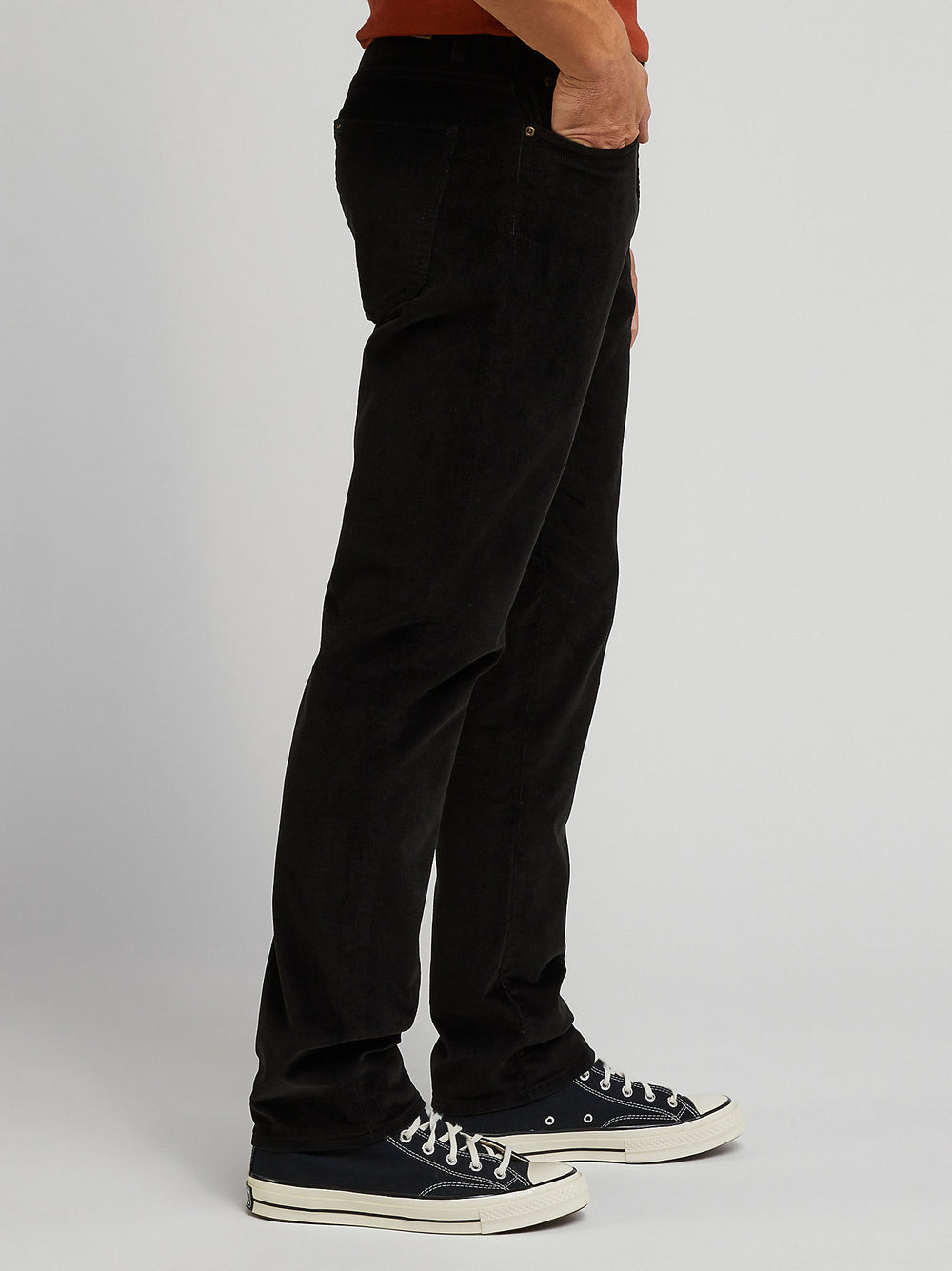Person wearing black pants and black sneakers on a plain background