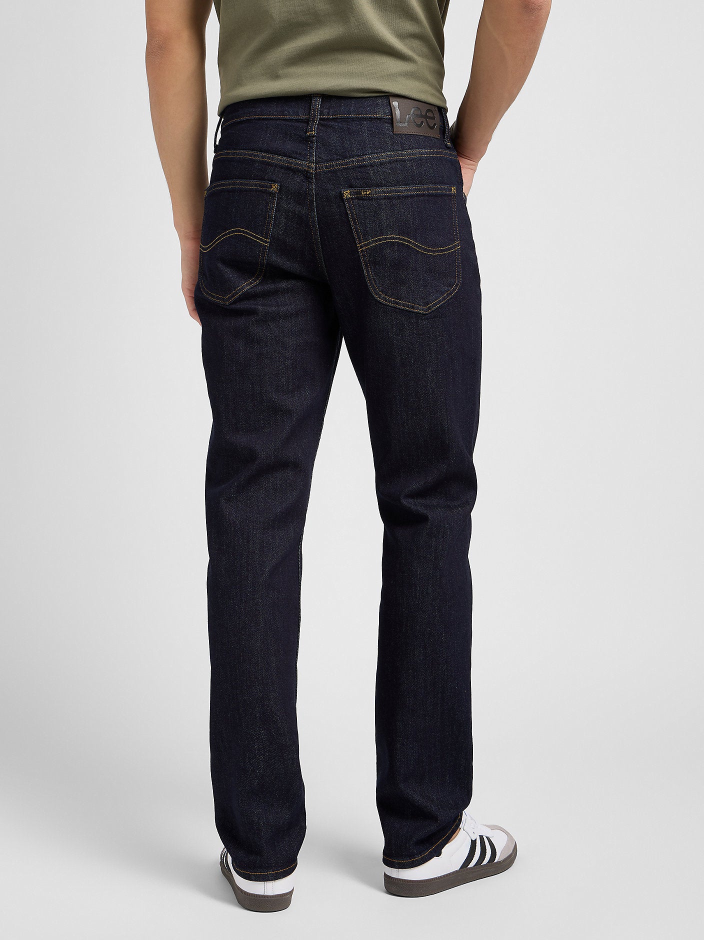 Person wearing dark blue jeans on a plain background