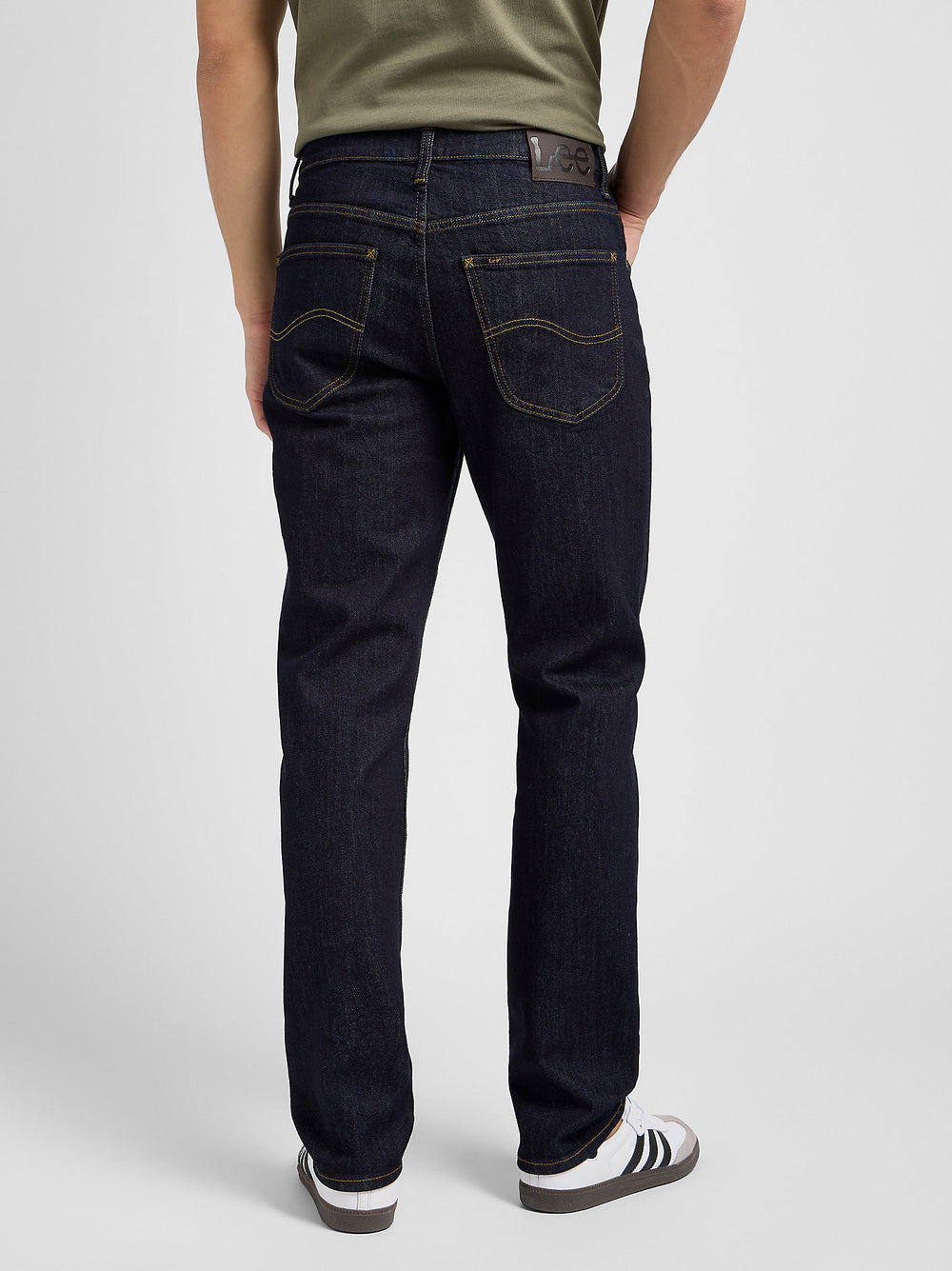 Person wearing dark blue jeans on a plain background
