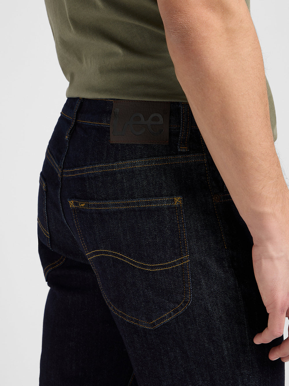 Person wearing dark blue jeans with a visible Lee brand label on a white background