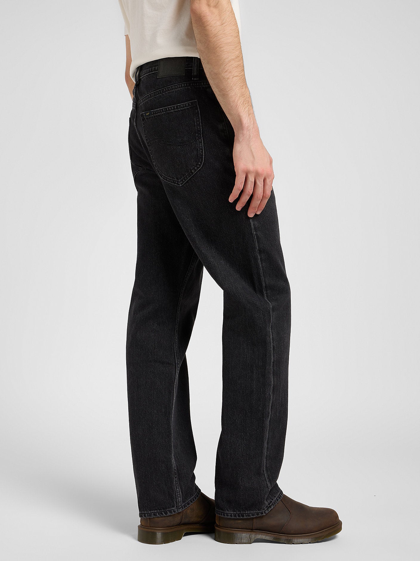 Person wearing black jeans and brown boots on a white background