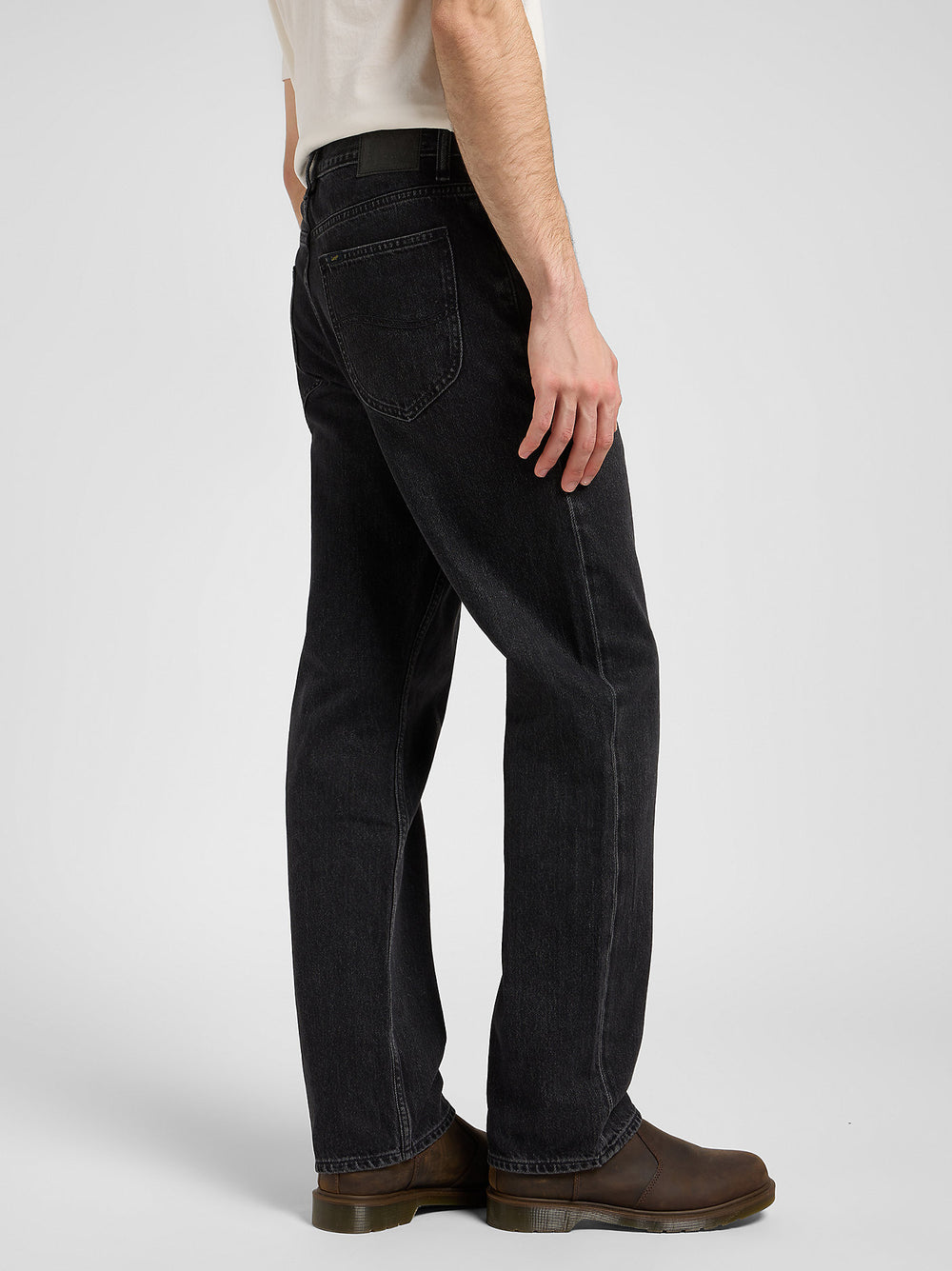 Person wearing black jeans and brown boots on a white background