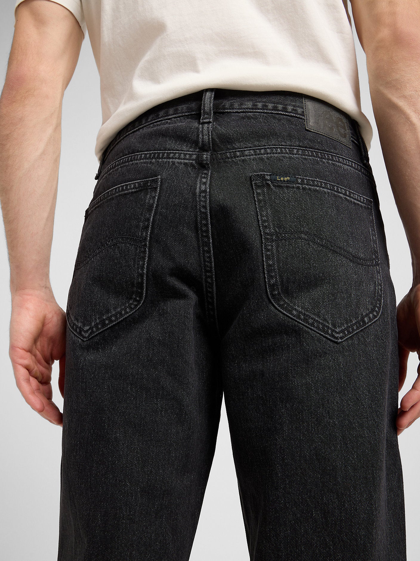 Person wearing black jeans with a plain background