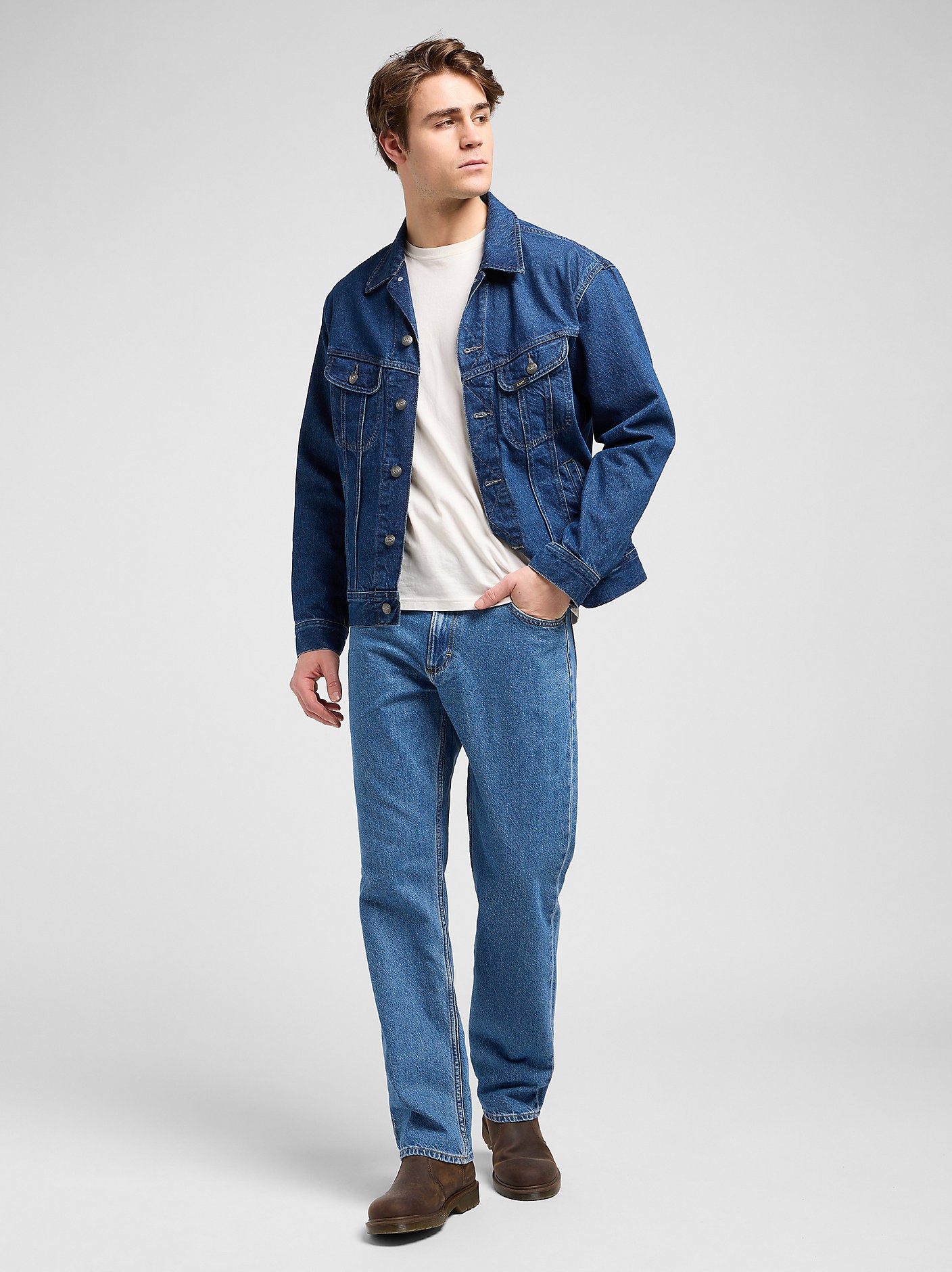 Man wearing a blue denim jacket and jeans on a white background