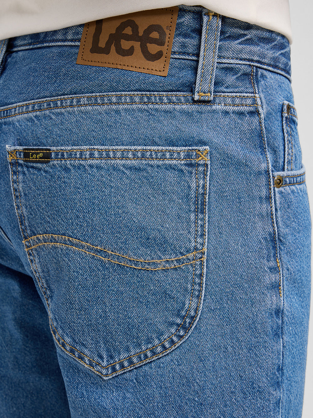 Close-up of blue jeans with a visible Lee brand label on the back pocket.