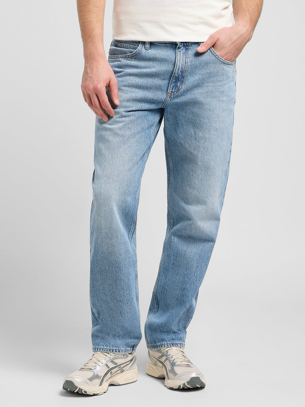 Person wearing light blue jeans on a plain background