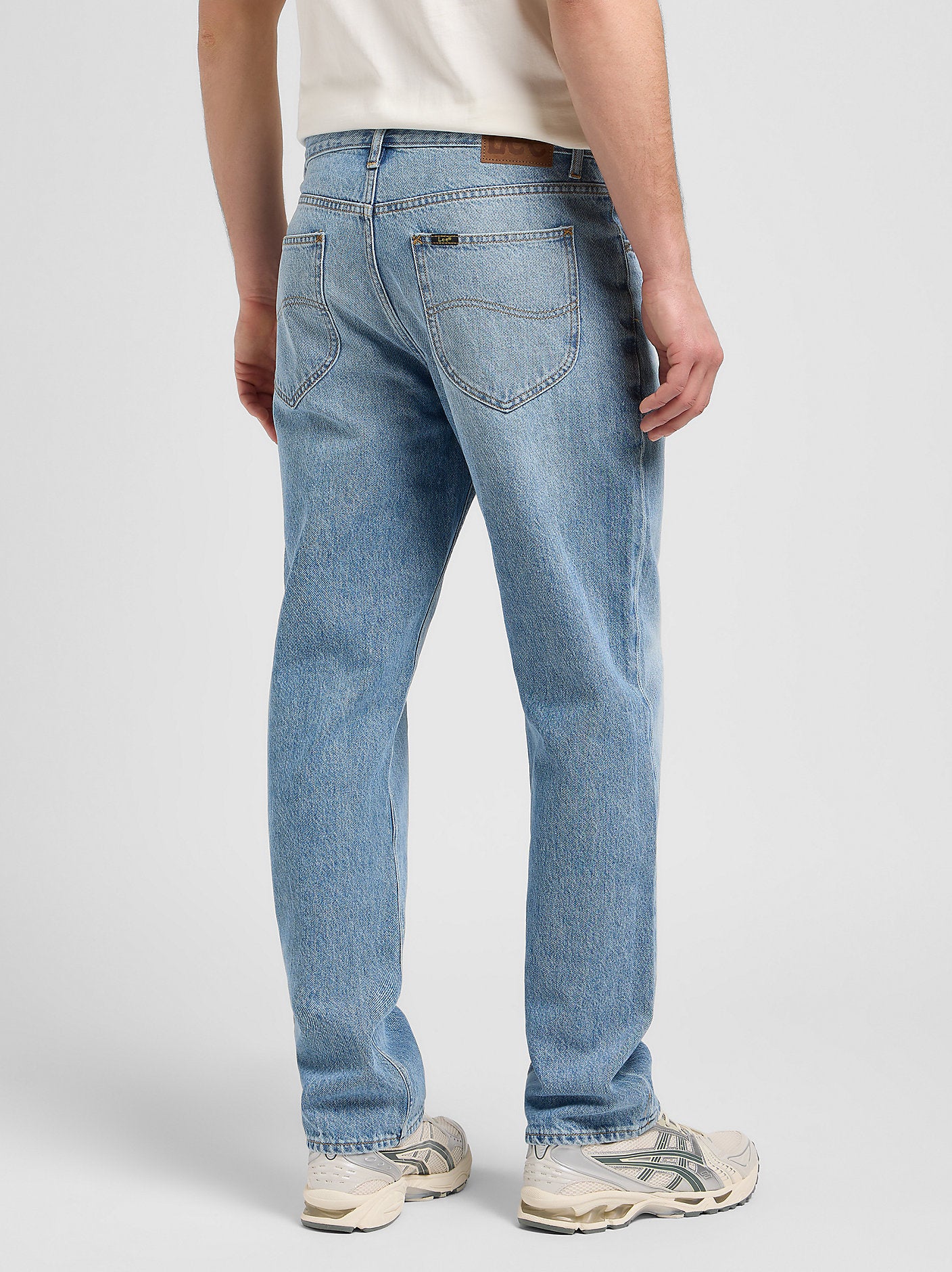 Person wearing light blue jeans on a plain background