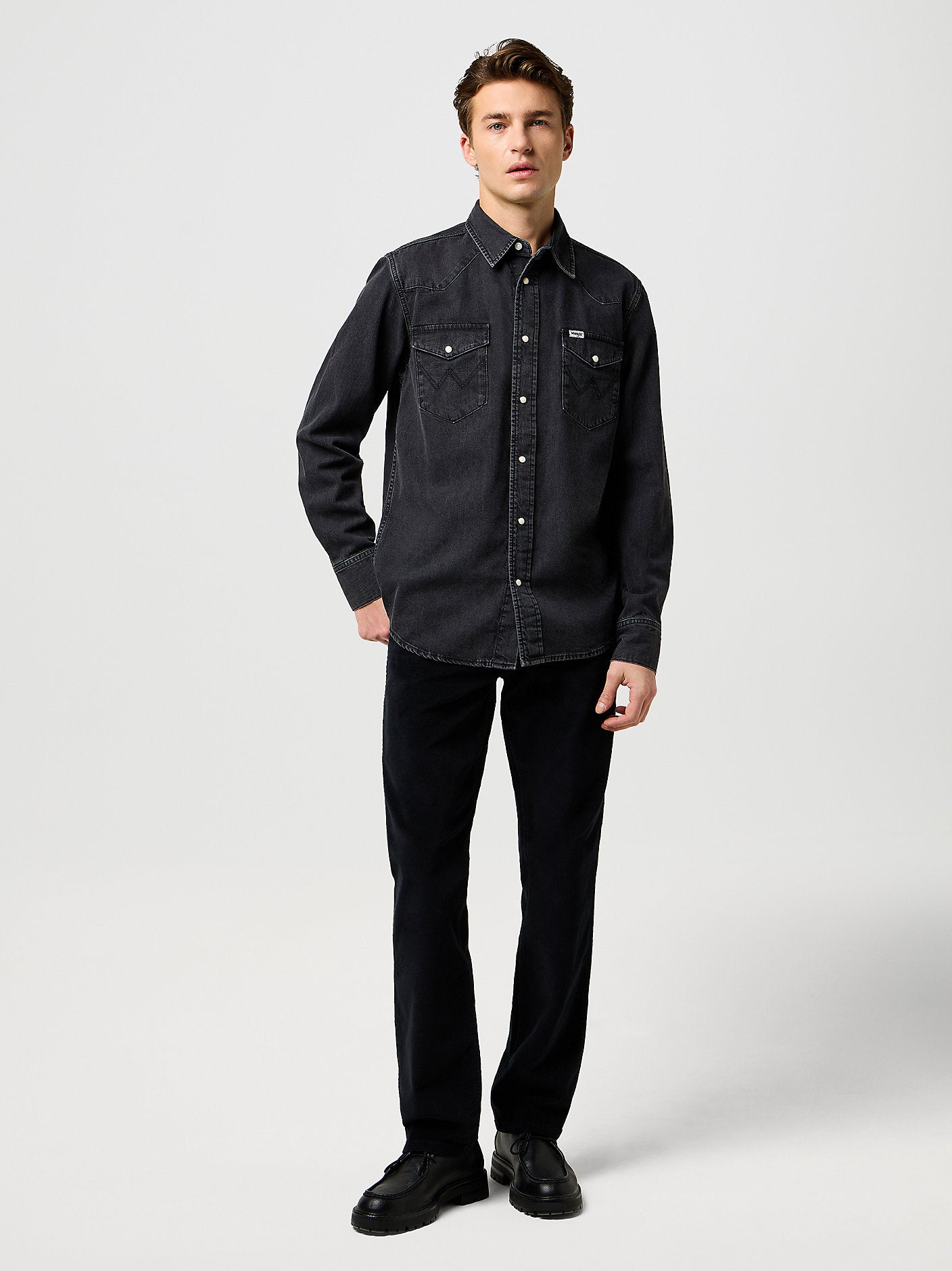 Man wearing a black denim shirt and pants on a white background