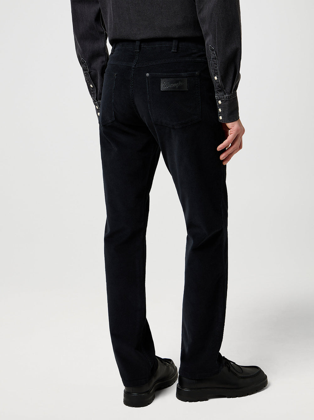 Person wearing black pants with button details on a white background