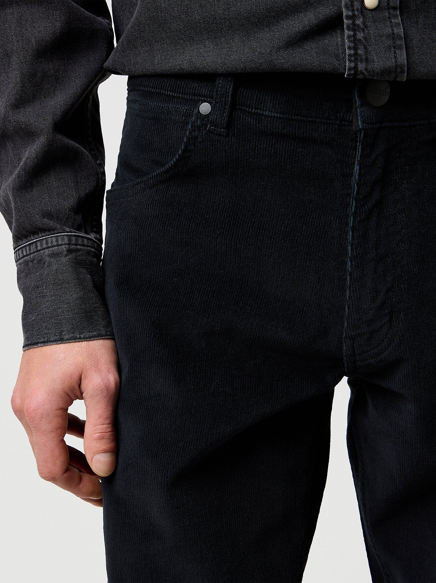 Person wearing black jeans with a plain background