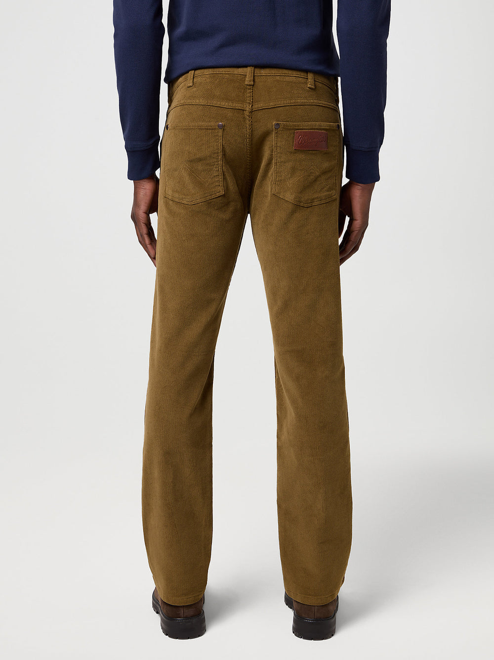 Brown corduroy pants worn by a person on a white background