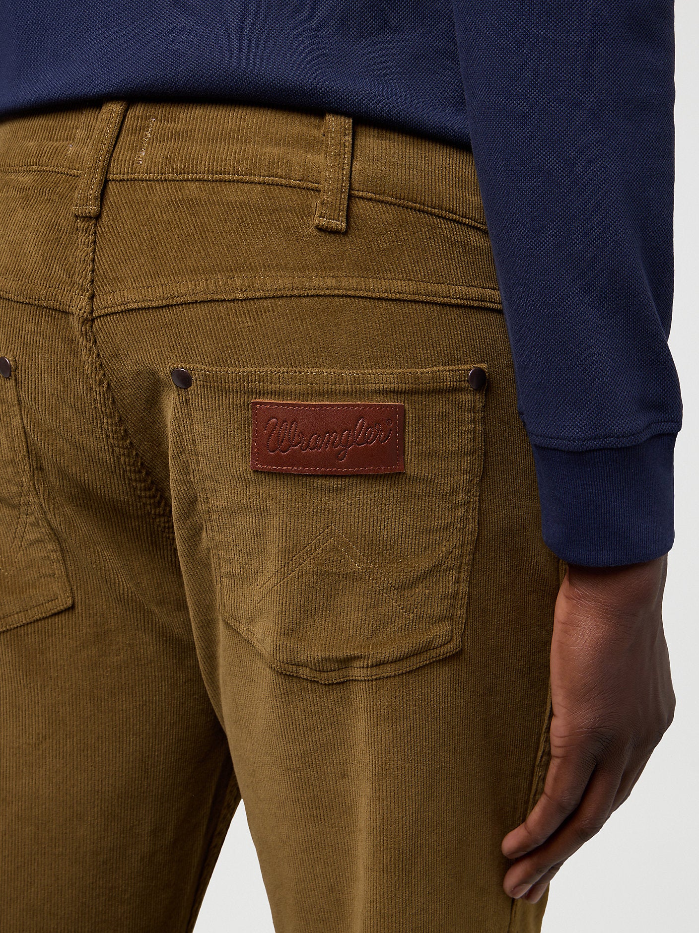 Brown corduroy pants with a Wrangler patch on a white background