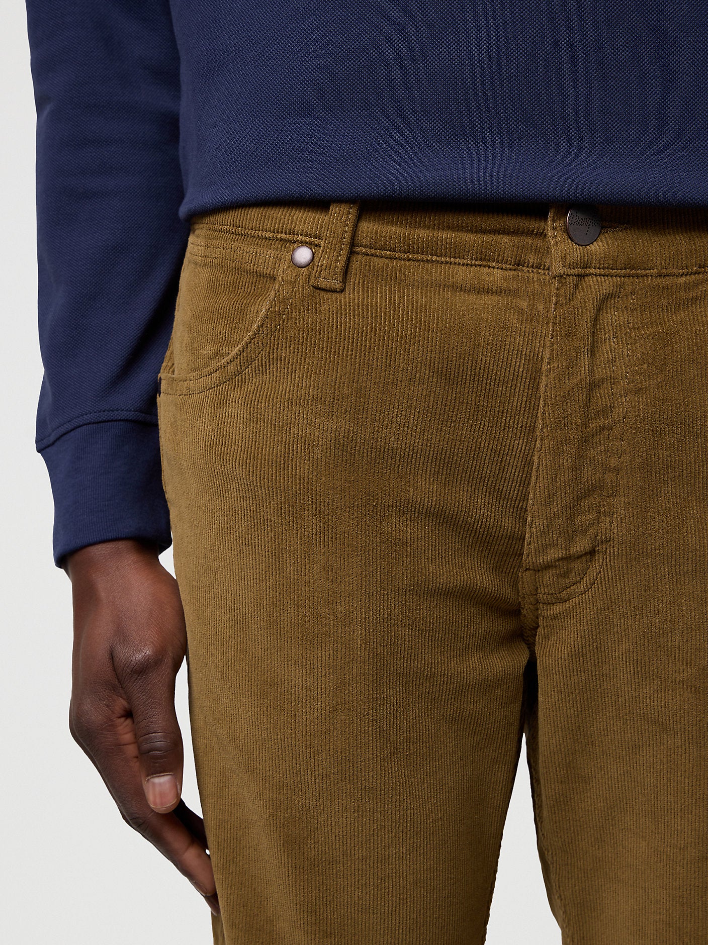 Brown corduroy pants worn with a blue shirt on a light gray background
