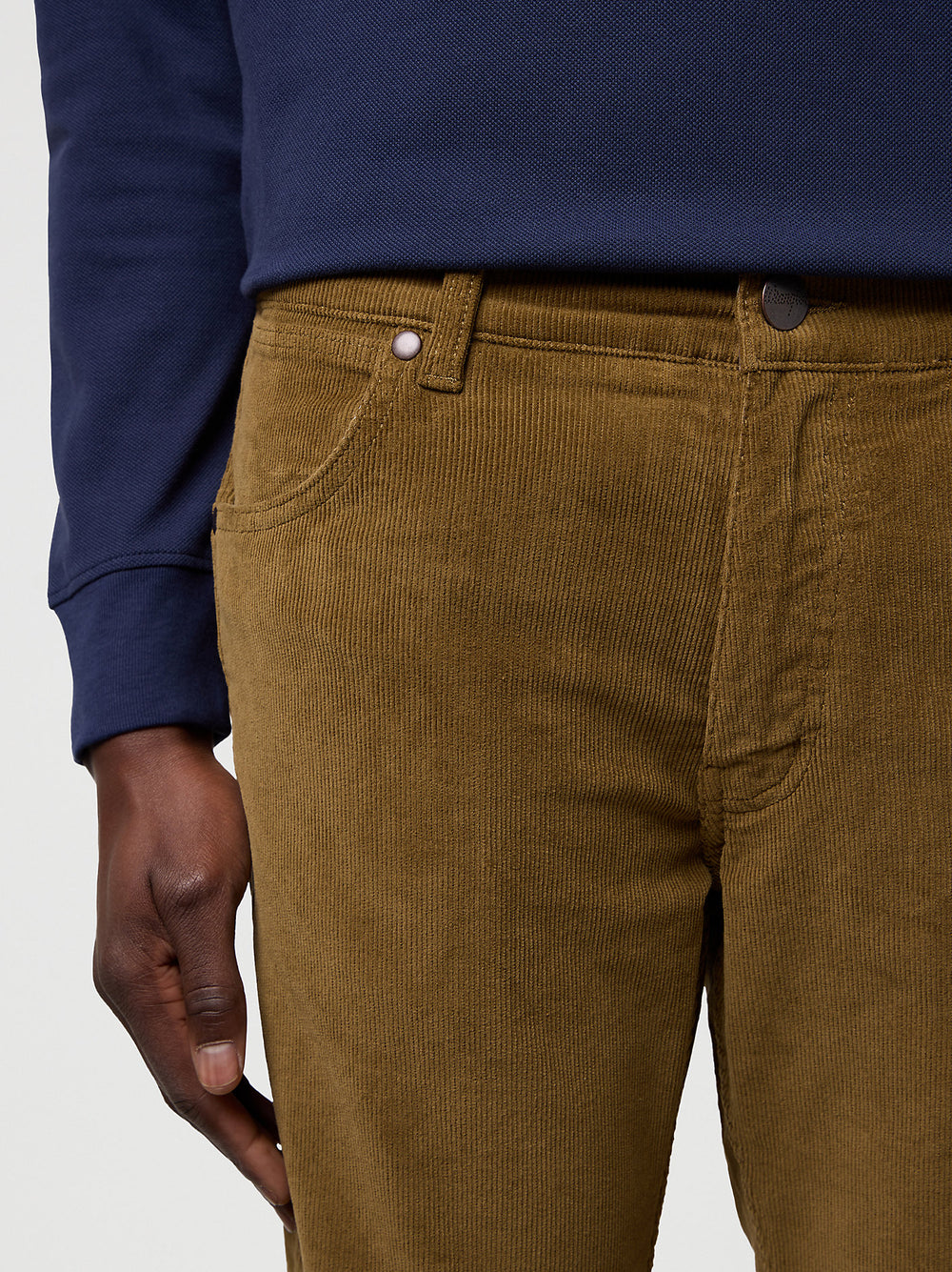 Brown corduroy pants worn with a blue shirt on a light gray background