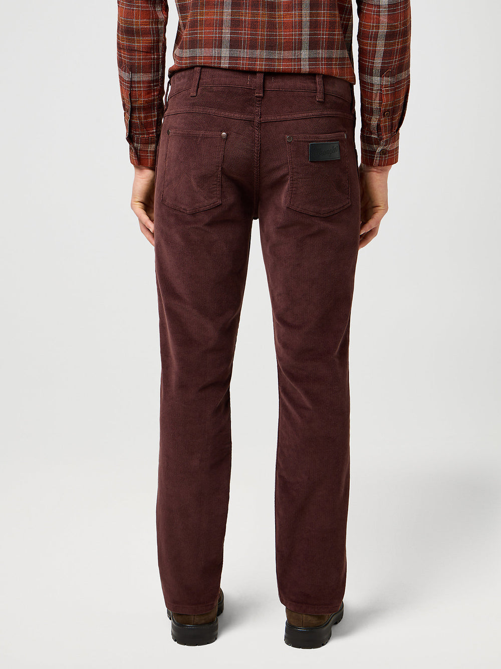 Brown corduroy pants worn by a person on a white background