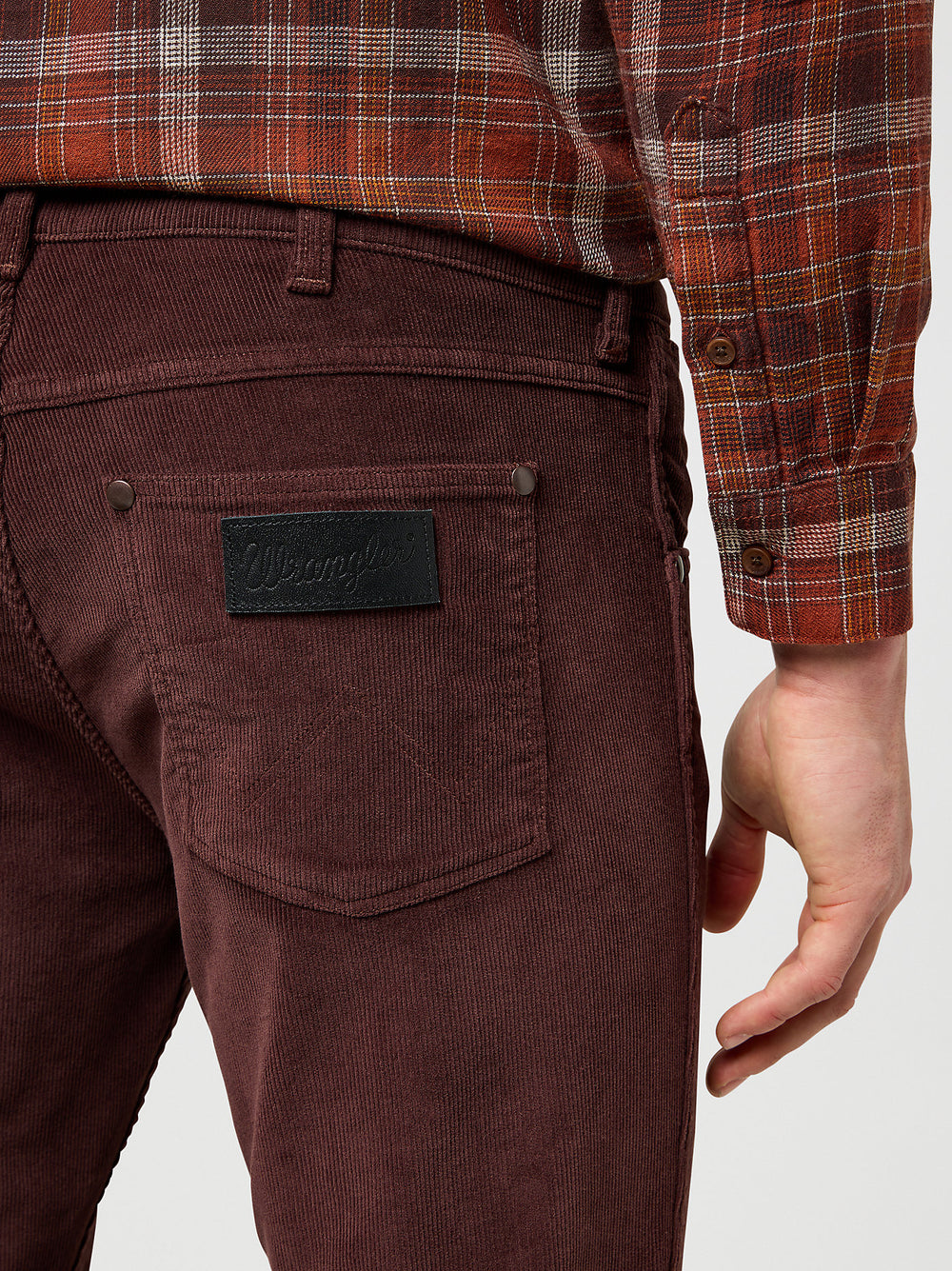 Brown corduroy pants with a brand logo on a plain background