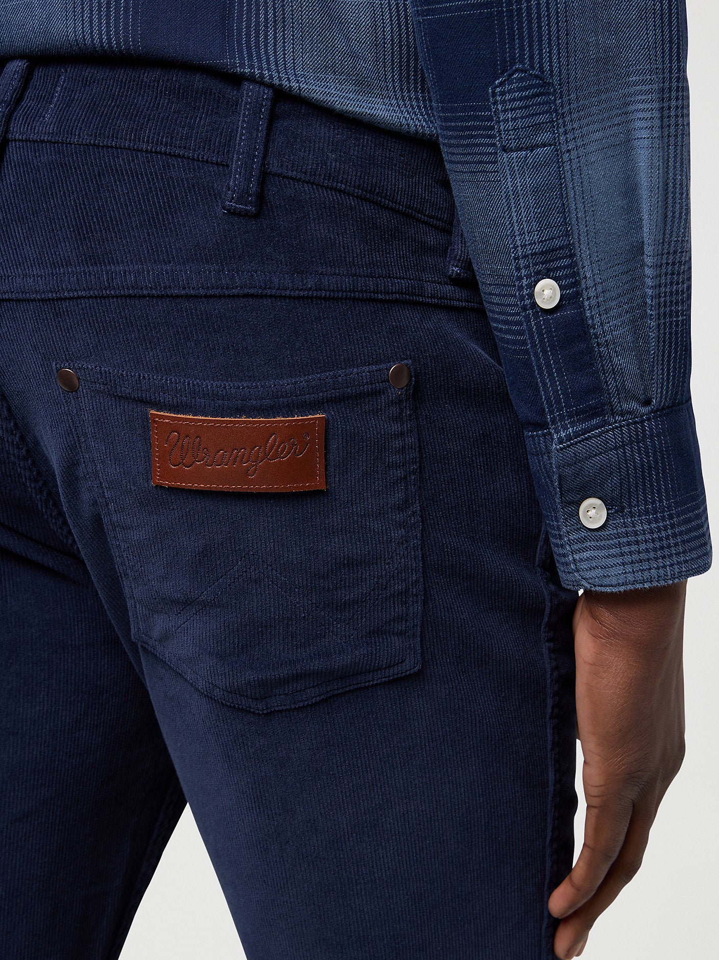 Navy blue pants with a leather patch on the pocket, worn by a person.