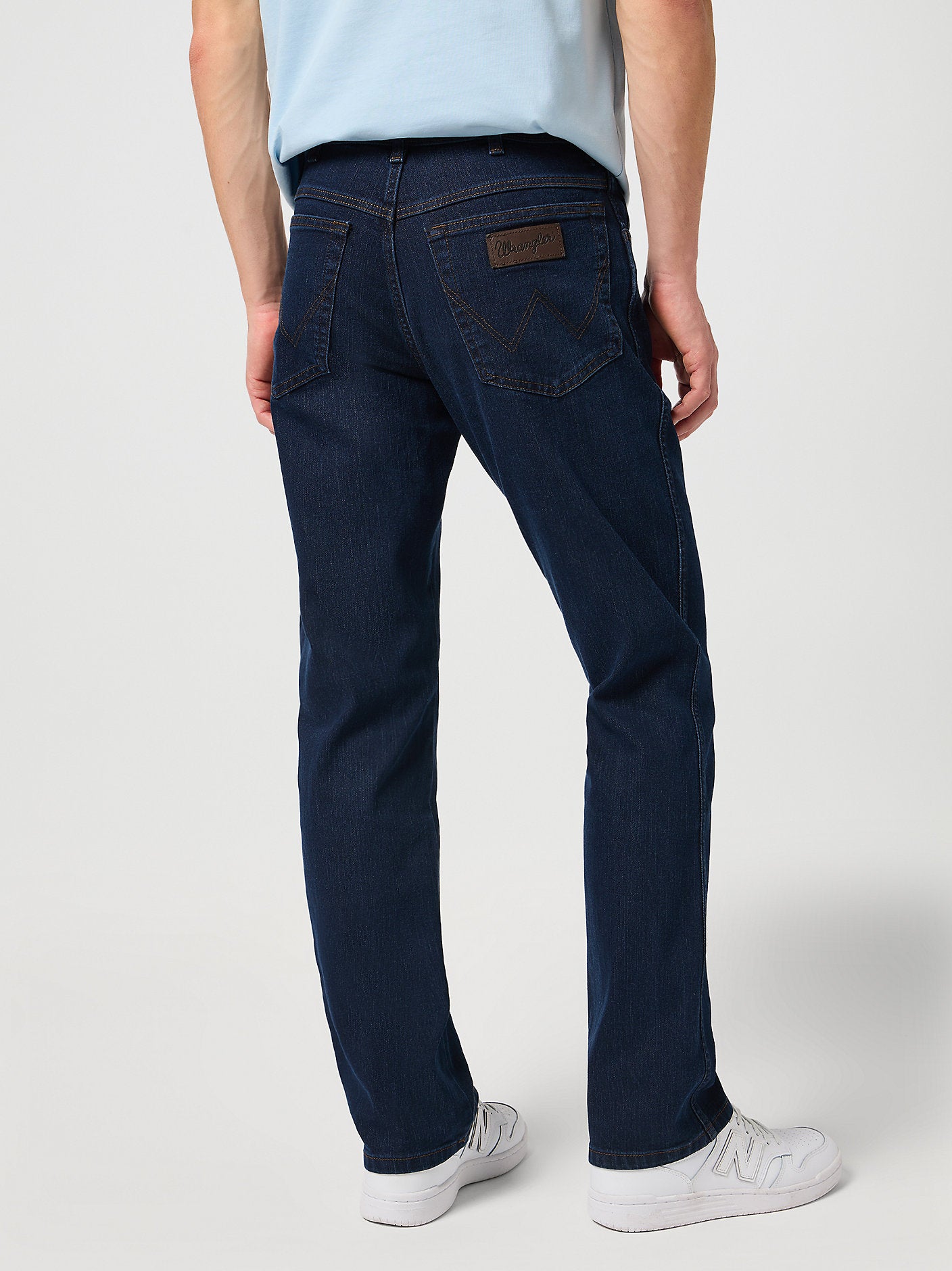 Person wearing dark blue jeans on a white background
