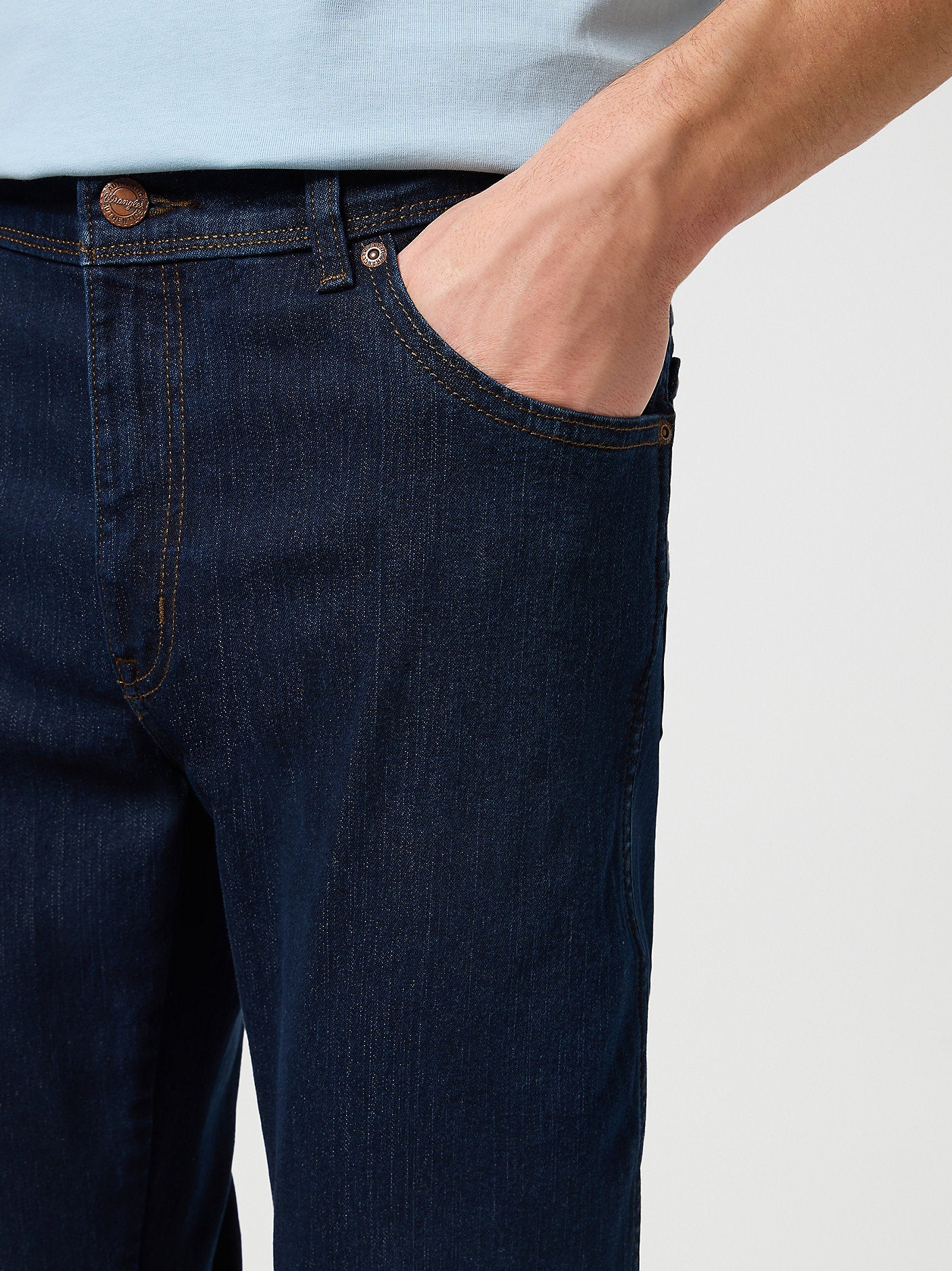 Person wearing dark blue jeans with a light background