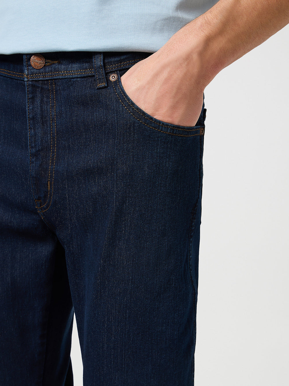 Person wearing dark blue jeans with a light background