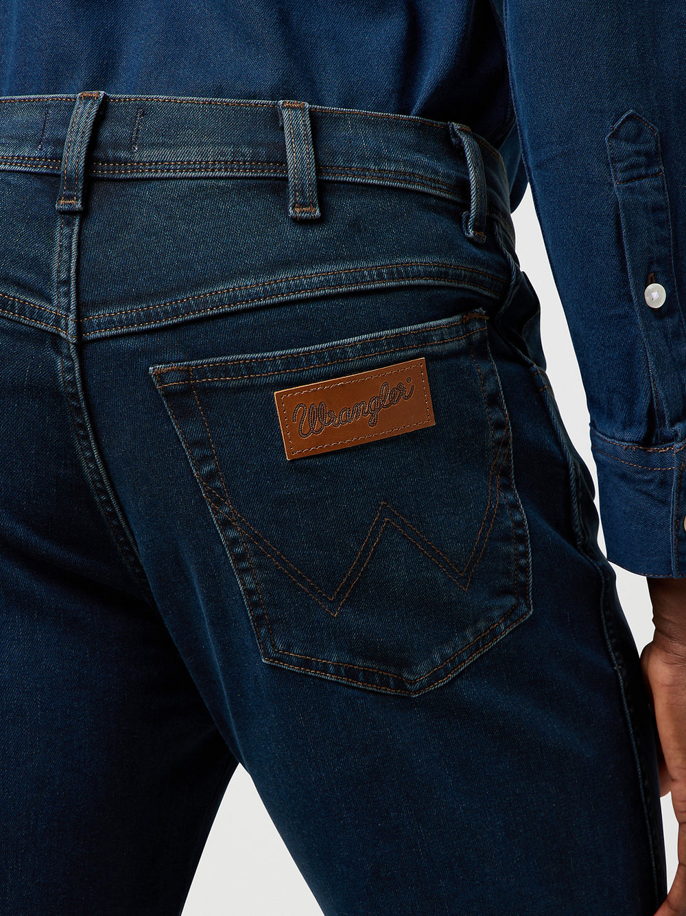 Close-up of blue jeans with a brand patch on a white background