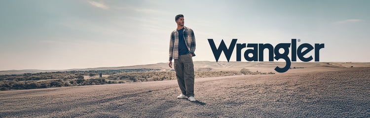 Person standing in a desert landscape with 'Wrangler' logo